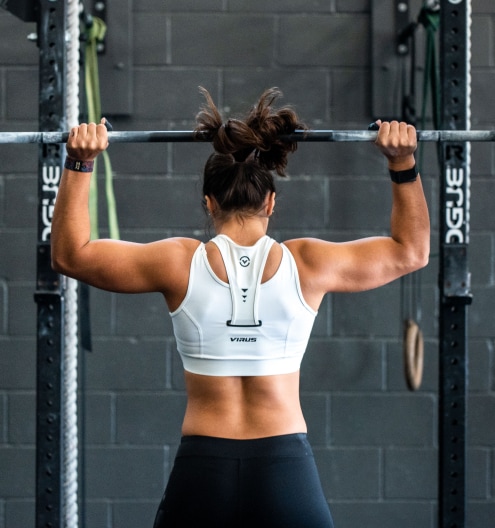 Woman lifting a barbell overhead during a weight loss program workout