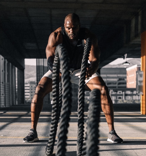 Man training with battle ropes as part of a wellness program